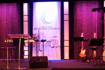 front view of stage with magenta pink LED wash on wall at East Coast Believers Church, Casselberry, FL, USA