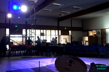 stage lit with blue and white LEDs with people working in the background on equipment inside First Baptist Church of Kent - Kent, WA, USA