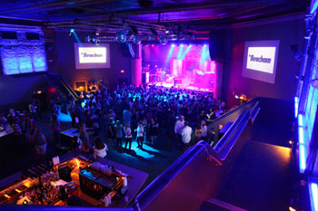 upstairs looking down at the crowd waiting for concert to start screens on both sides of the stage say The Beacham the theatre has blue purple magenta wash  The Beacham - Orlando, Florida, USA