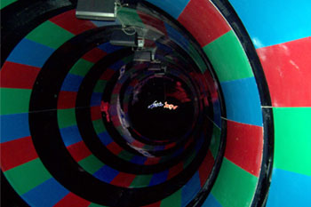 round walls with alternate black and multicolor blue, green, red stripes inside the Brainwash Water Slide, Wet 'n Wild - Orlando, Florida, USA