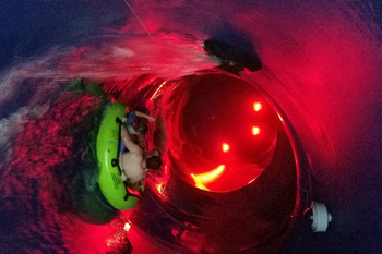 guests on yellow raft riding throug vibrant color of red LED fixtures illuminating inside the Python Funnel Water Slide, P.A.R.C. - Frankston VIC, Australia